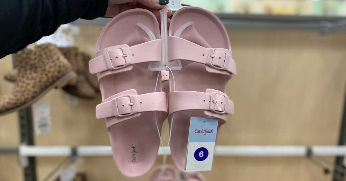 hand holding a pair of birkenstock like sandals pink in store