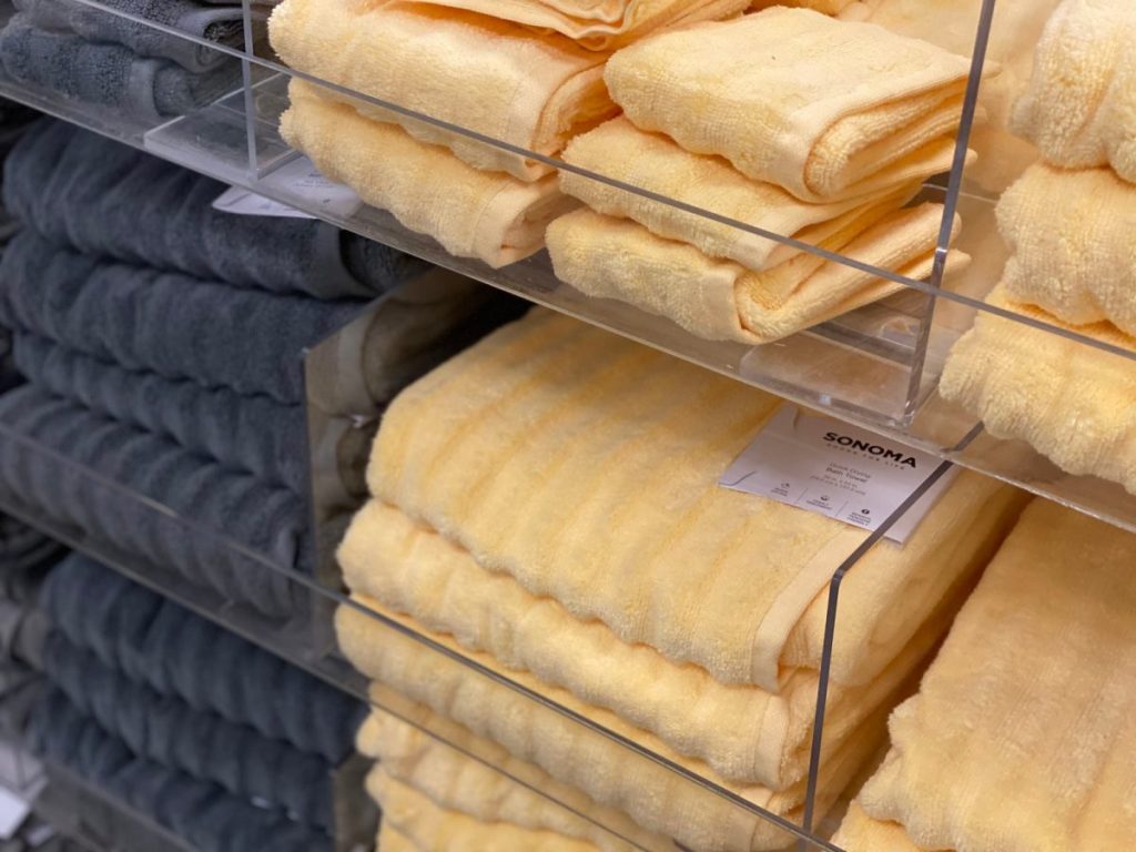 stacks of blue gray and yellow towels on clear shelves