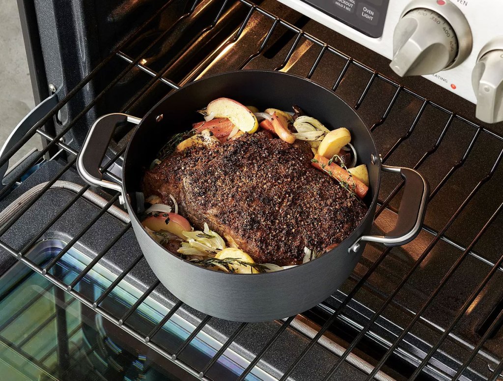 black stockpot on oven shelf with a roast inside of it