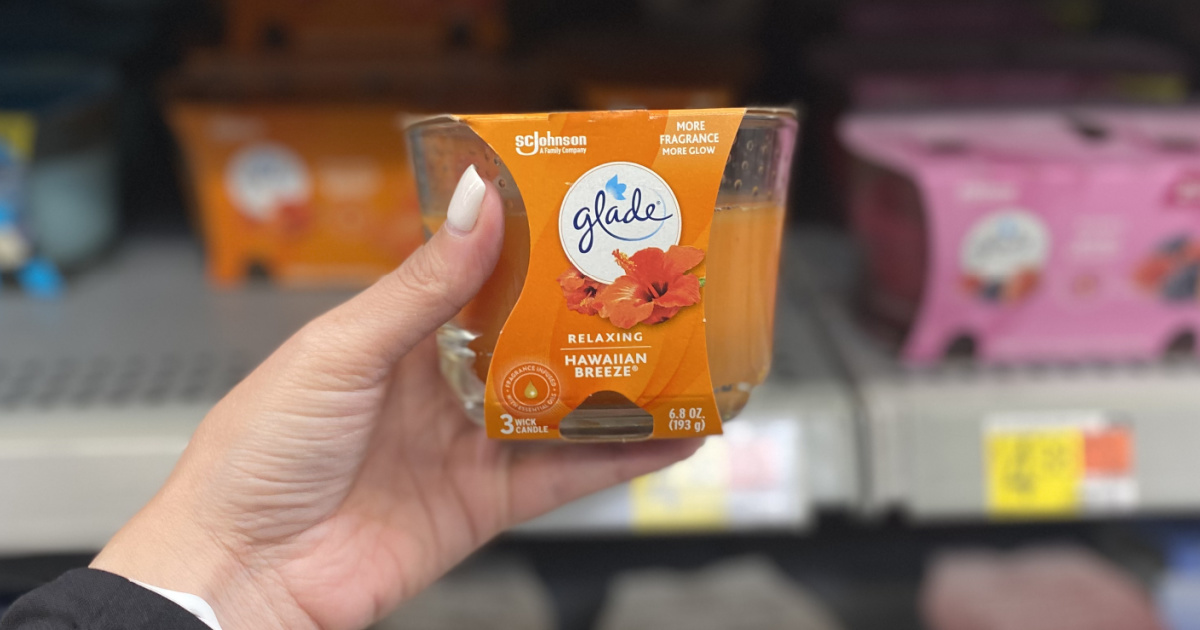 hand holding up an orange glade glass jar candle in front of a store shelf