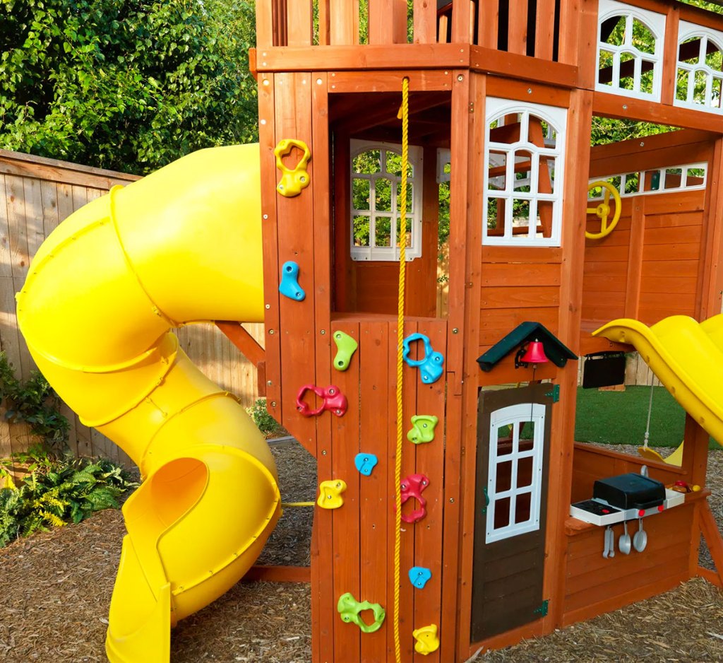 climbing wall and yellow spiral slide on backyard playset