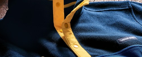 men's blue and yellow buttoned pullover on table next to keys