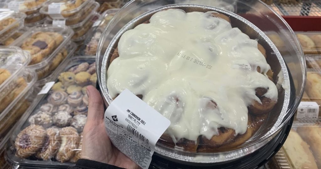 hand holding a tray of cinnamon rolls