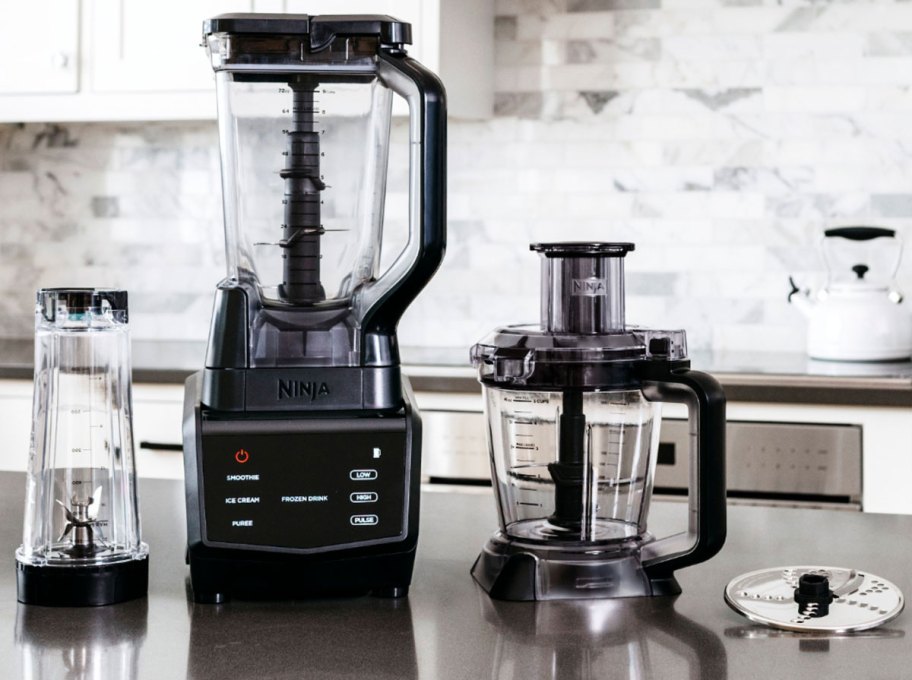 ninja blender on kitchen counter with single serve cup, food processor attachment, and blade