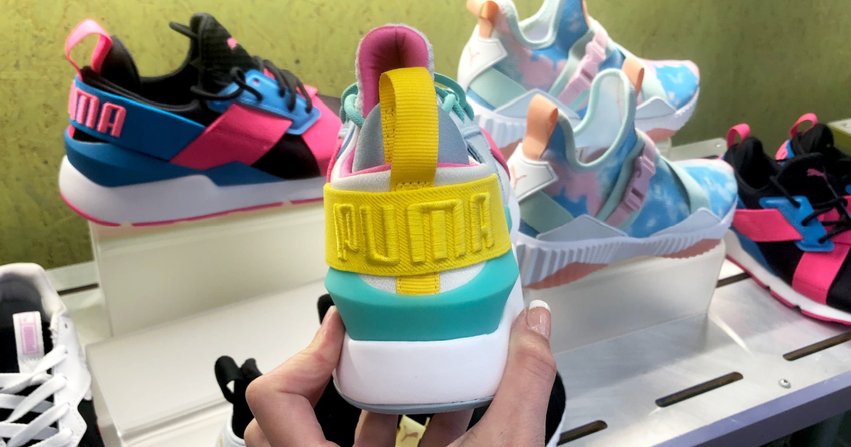 Hand holding kids PUMA brand shoes in-store