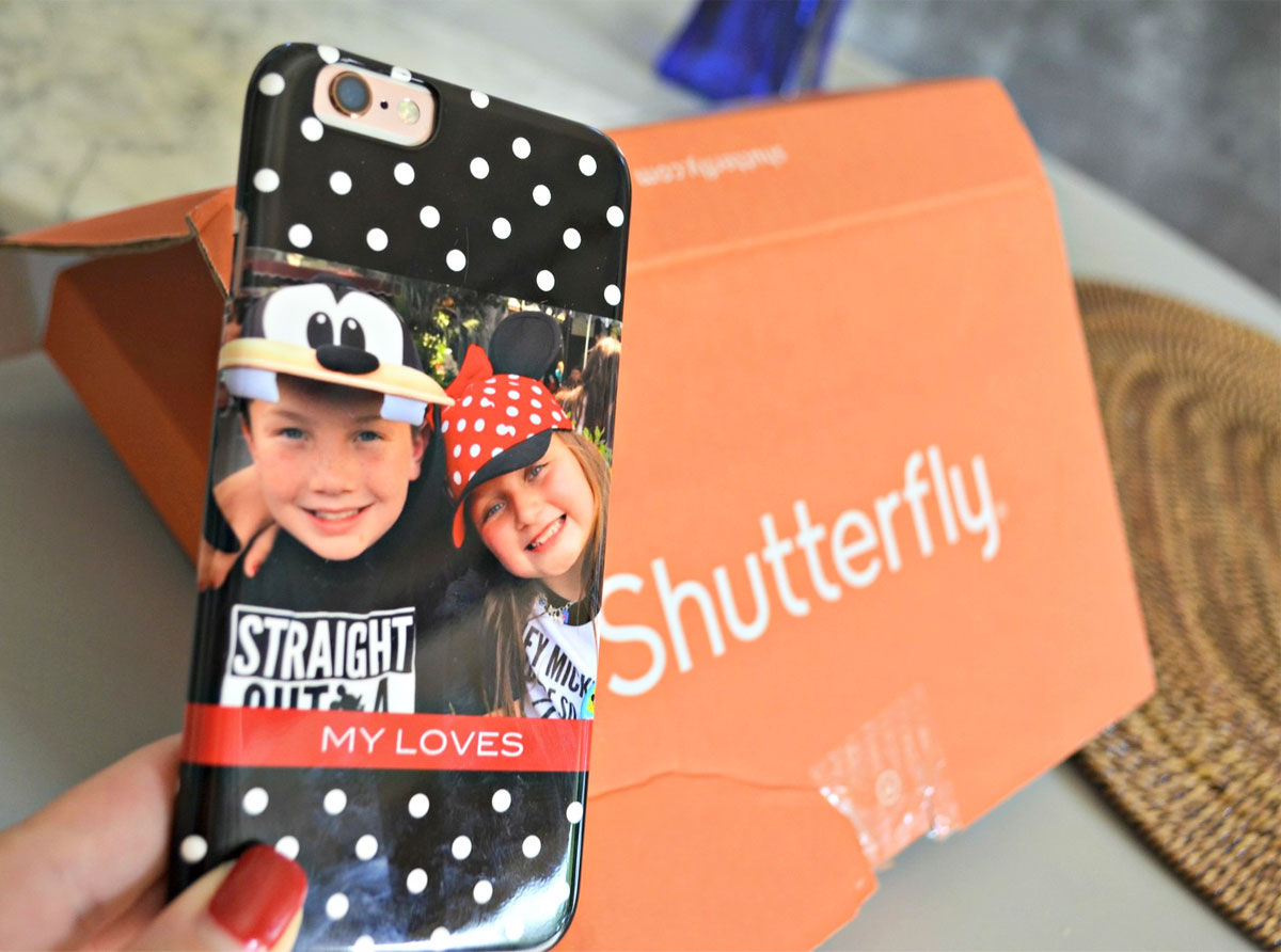 woman holding up a custom photo phone case with orange shutterfly shipping box in background