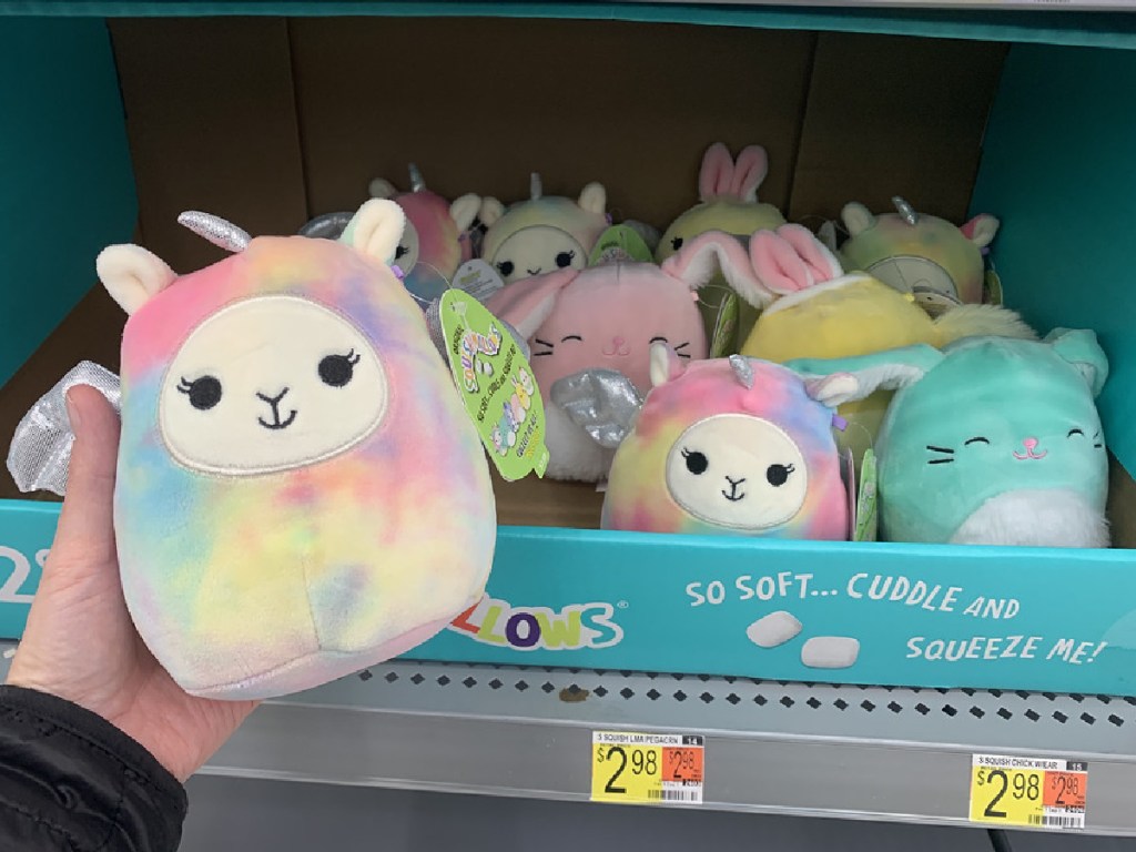 man's hand holding tie-dye plush animal in store