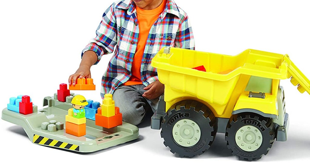 little boy playing with a toy dump truck and blocks