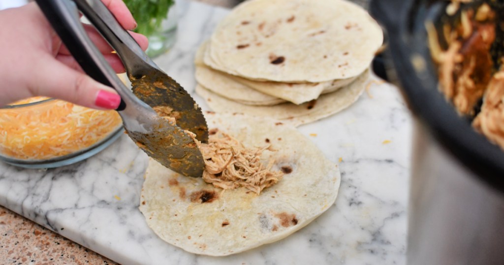 adding chicken to tortillas for taquitos