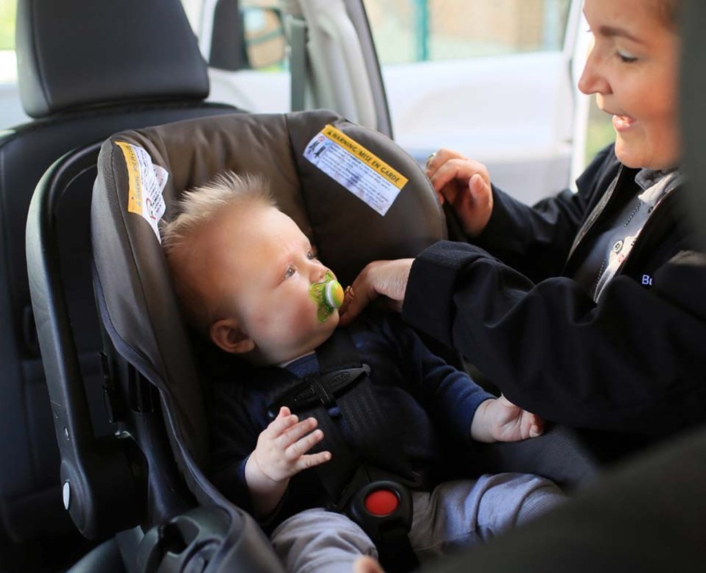 woman buckling baby in car seat