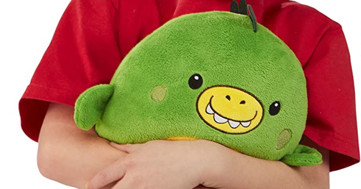 Green dinosaur huggle pet held by a child with a red short sleeve tee