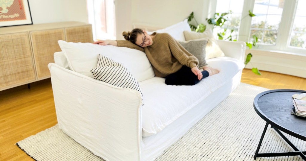 woman laying on white sofa in living room