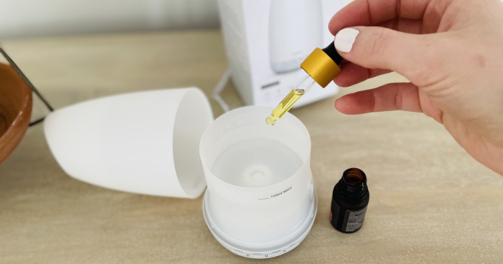 woman adding oil drops to a diffuser