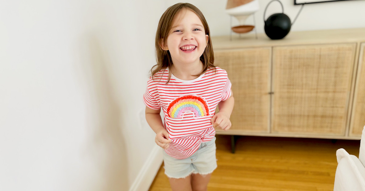 girl wearing colorful rainbow shirt smiling