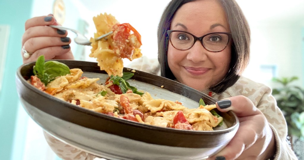 woman holding up a bowl of pasta