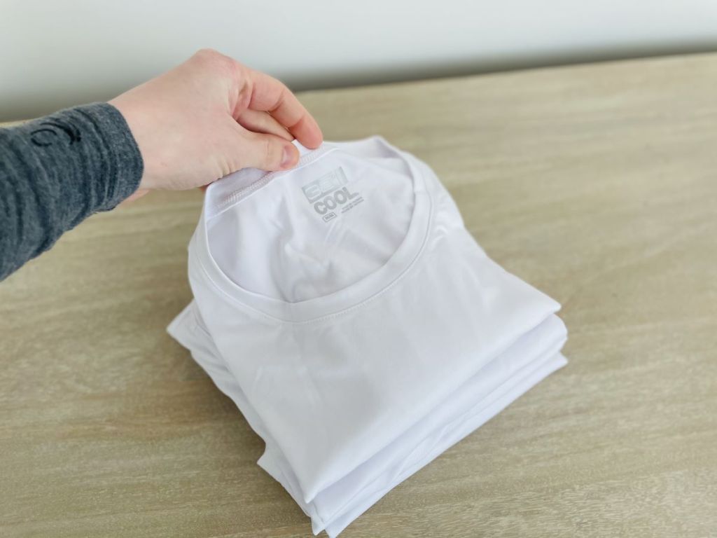 hand holding a stack of t-shirts