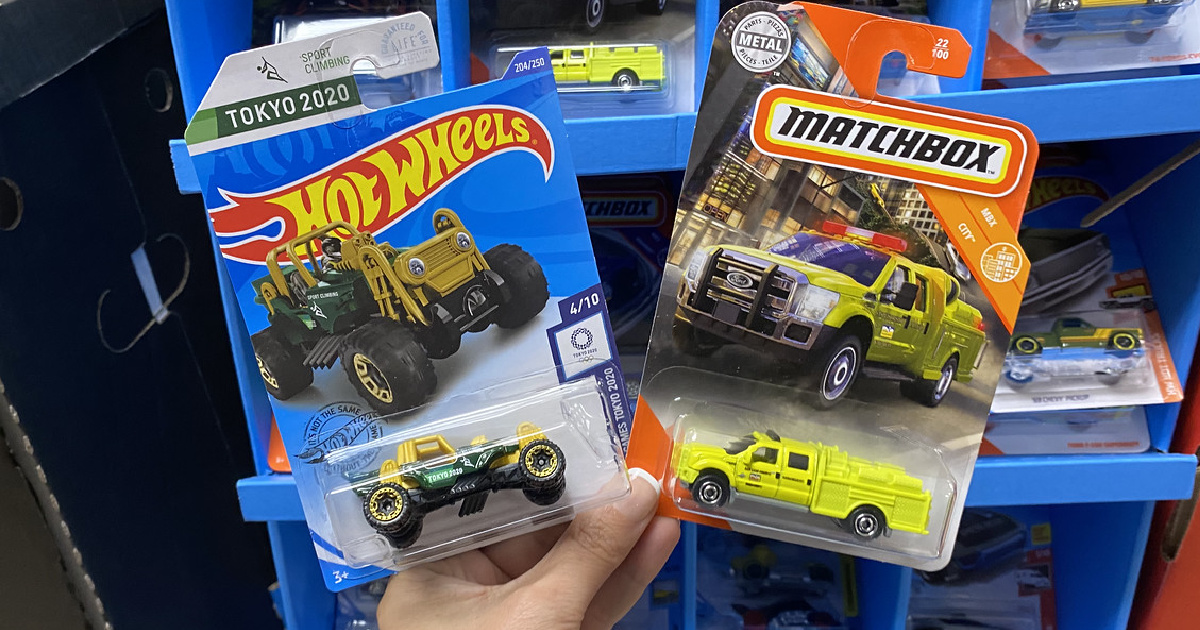 hand holding up two Hot Wheels Matchbox Cars