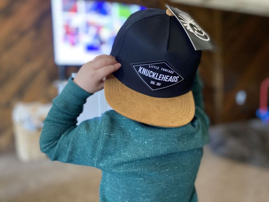 kid holding a hat on his head