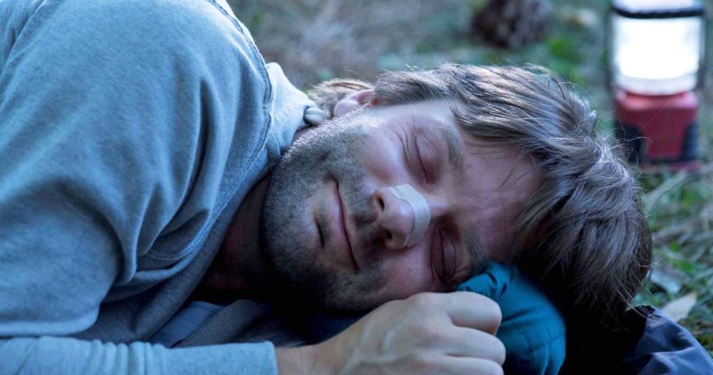 man sleeping with a breathe right nasal strip on his nose