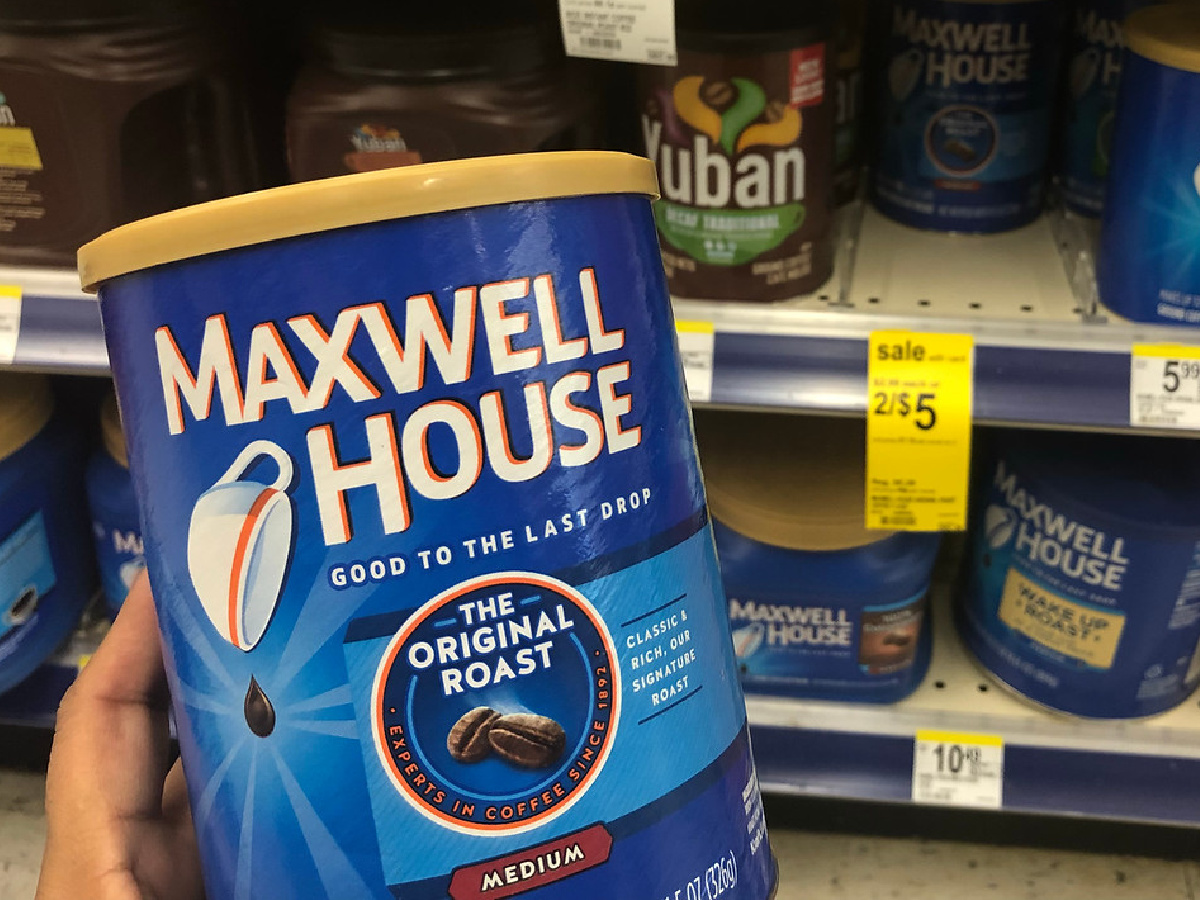 hand holding up a canister of maxwell house coffee in front of a store shelf