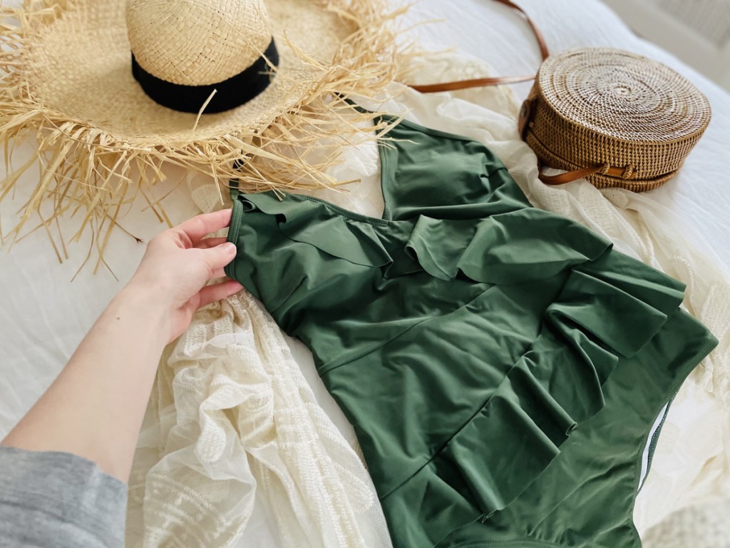 green swimsuit, straw hat and bag on bed