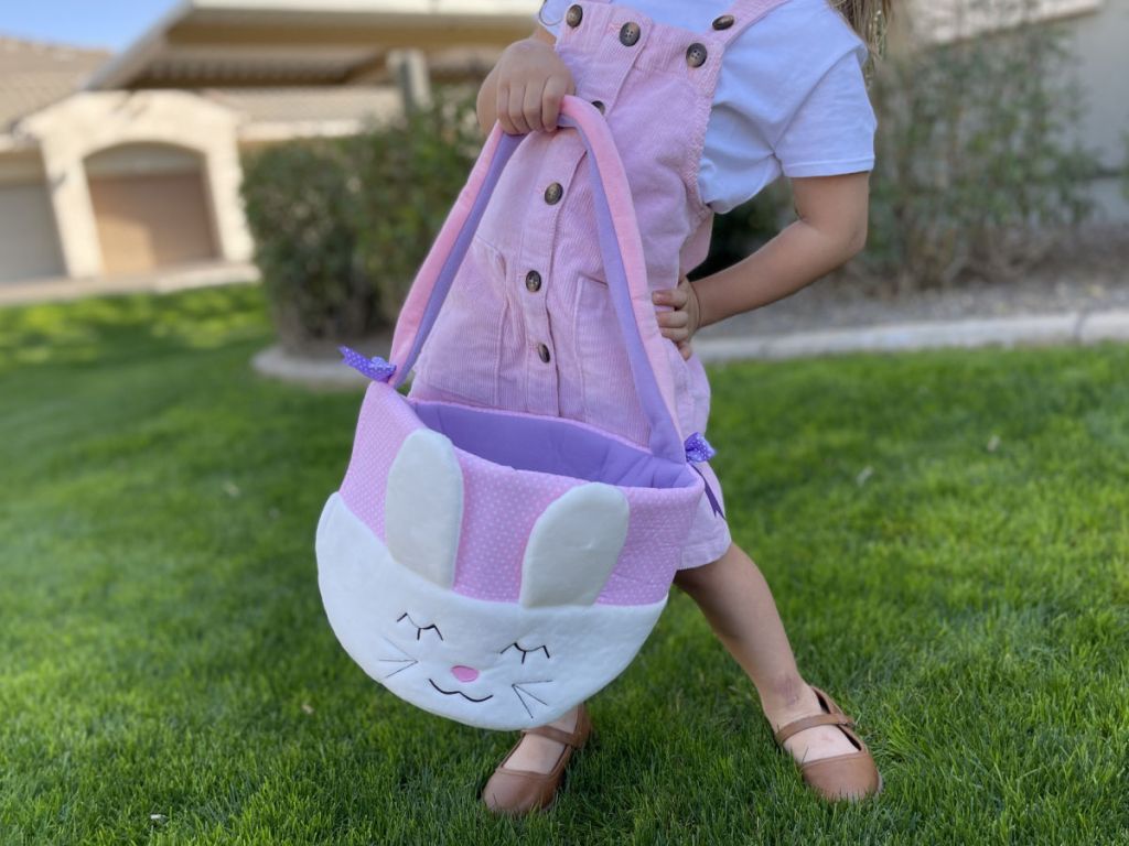 Little girl in pink dress holding large Easter basket