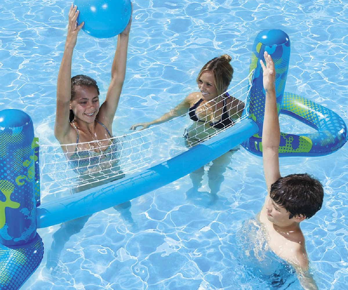 young boy and girls playing inflatable volleyball set in a pool