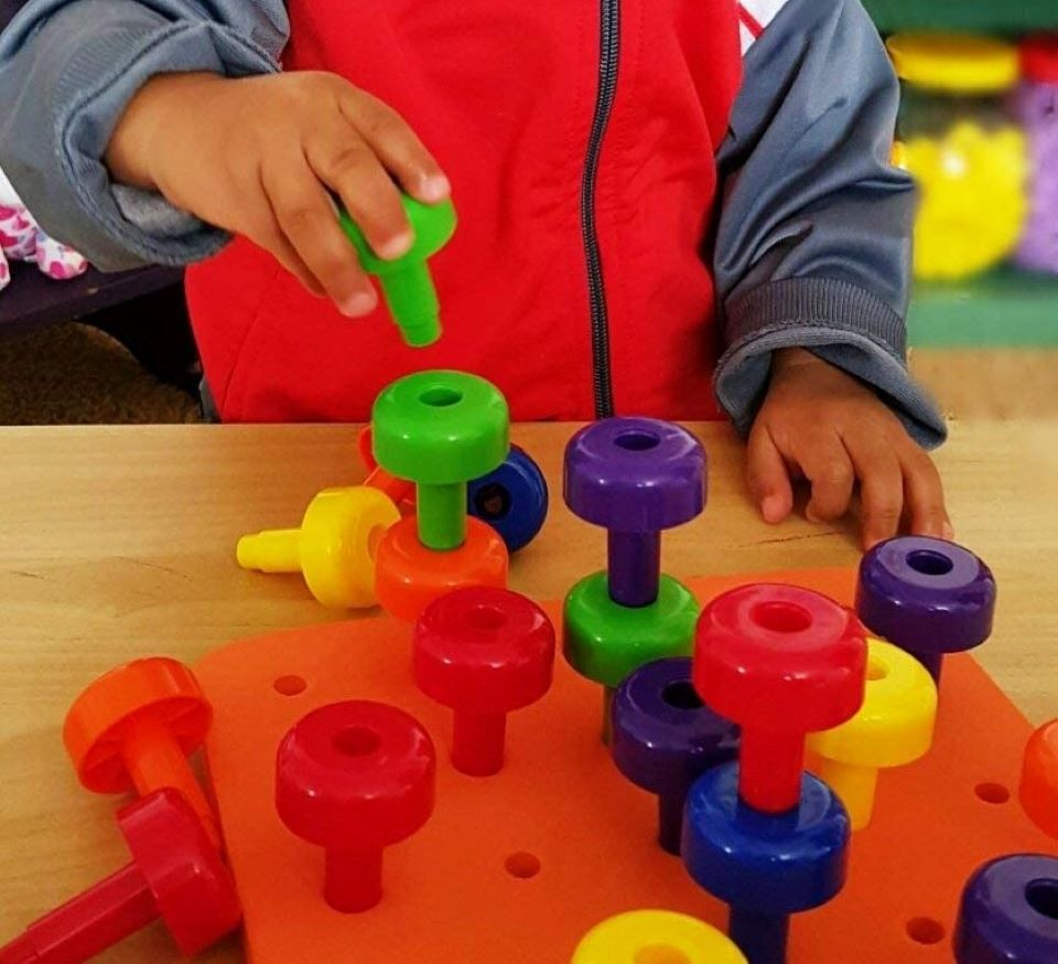 child playing with a pegboard toy