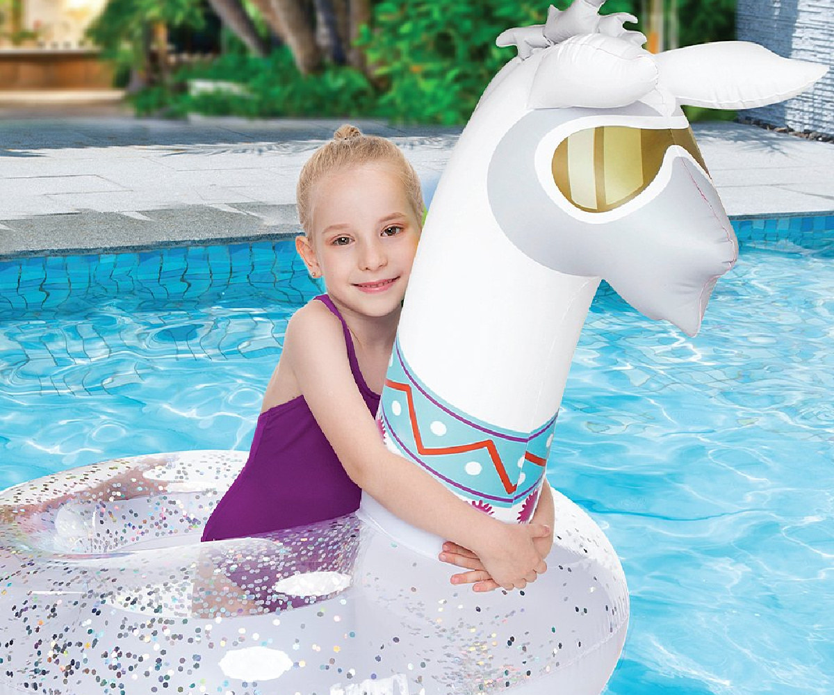 young girl in purple bathing suit on a glittery llama float in a pool