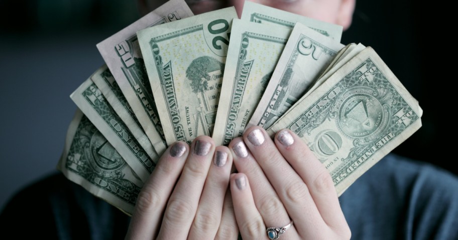 woman holding cash in front of face