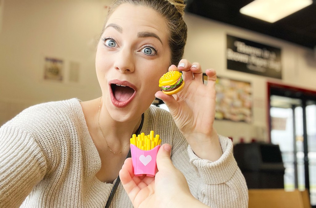 woman looking surprised holding miniature burger