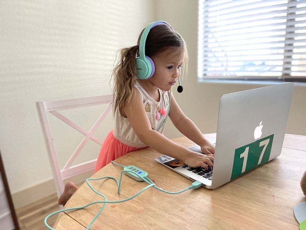 kid wearing headphone typing and staring at laptop