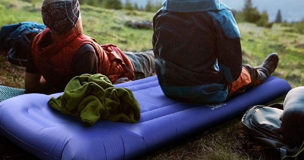 guys sitting on sable camping mat outside