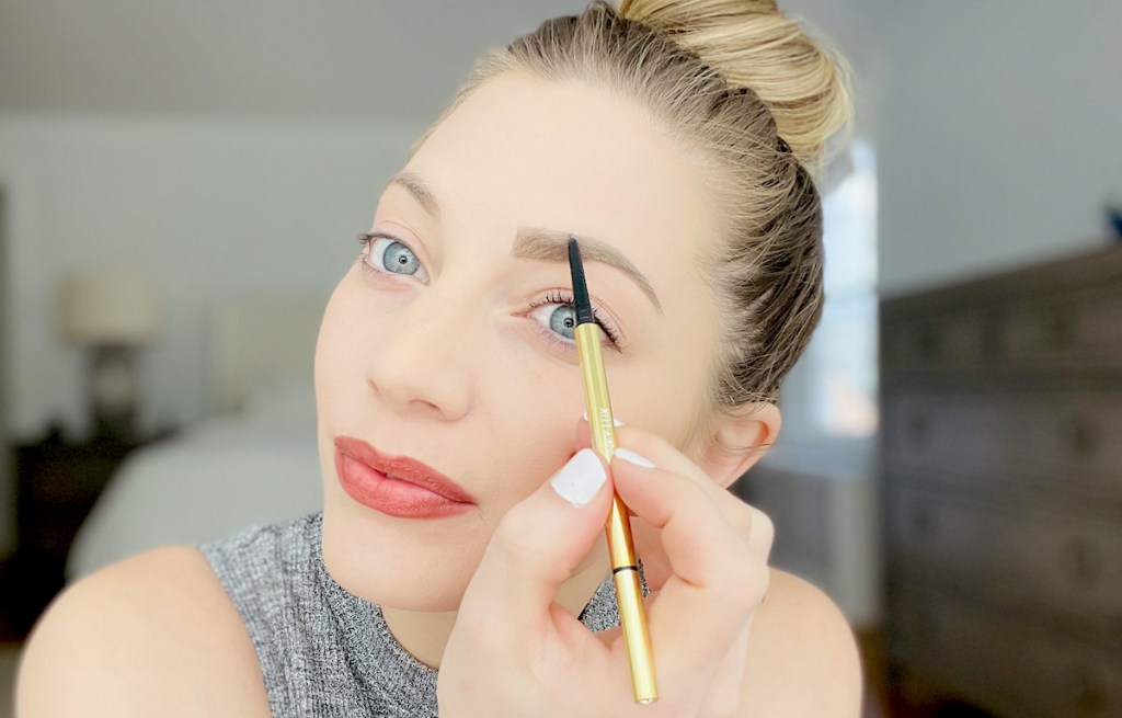 close up of woman doing eyebrows with gold winky lux unibrow pencil