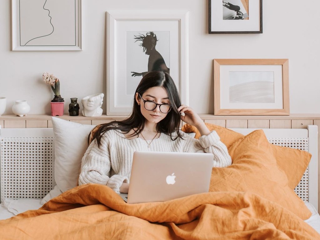 woman using a macbook in bed