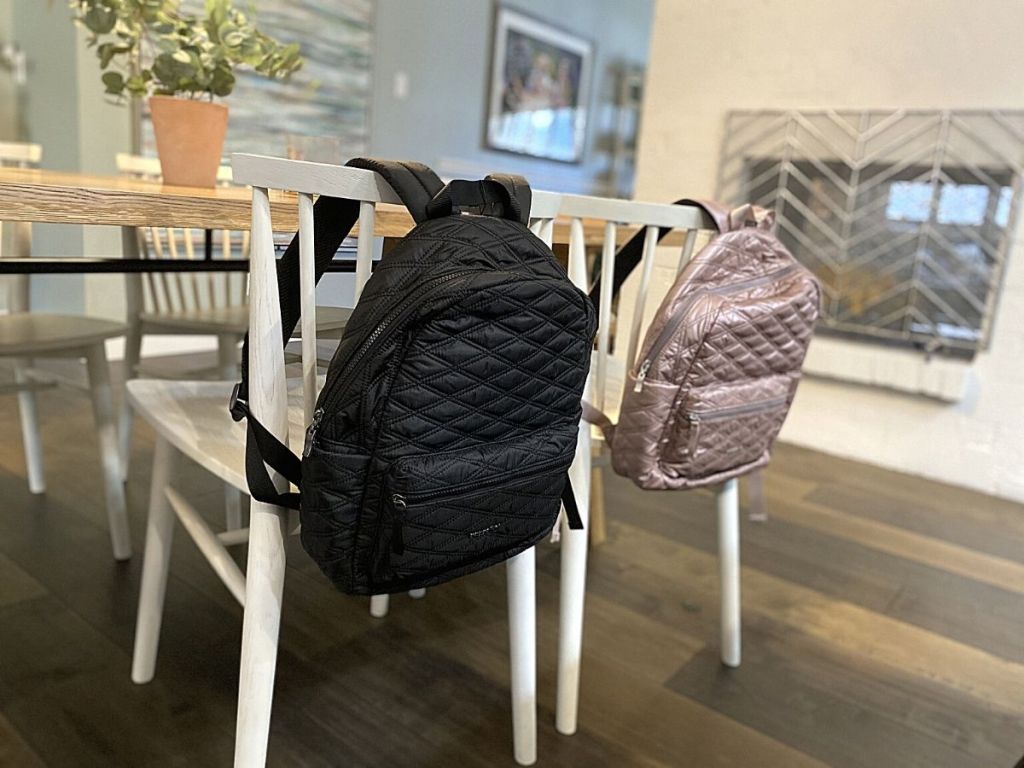 baggallini backpacks hanging on chairs in a dining room