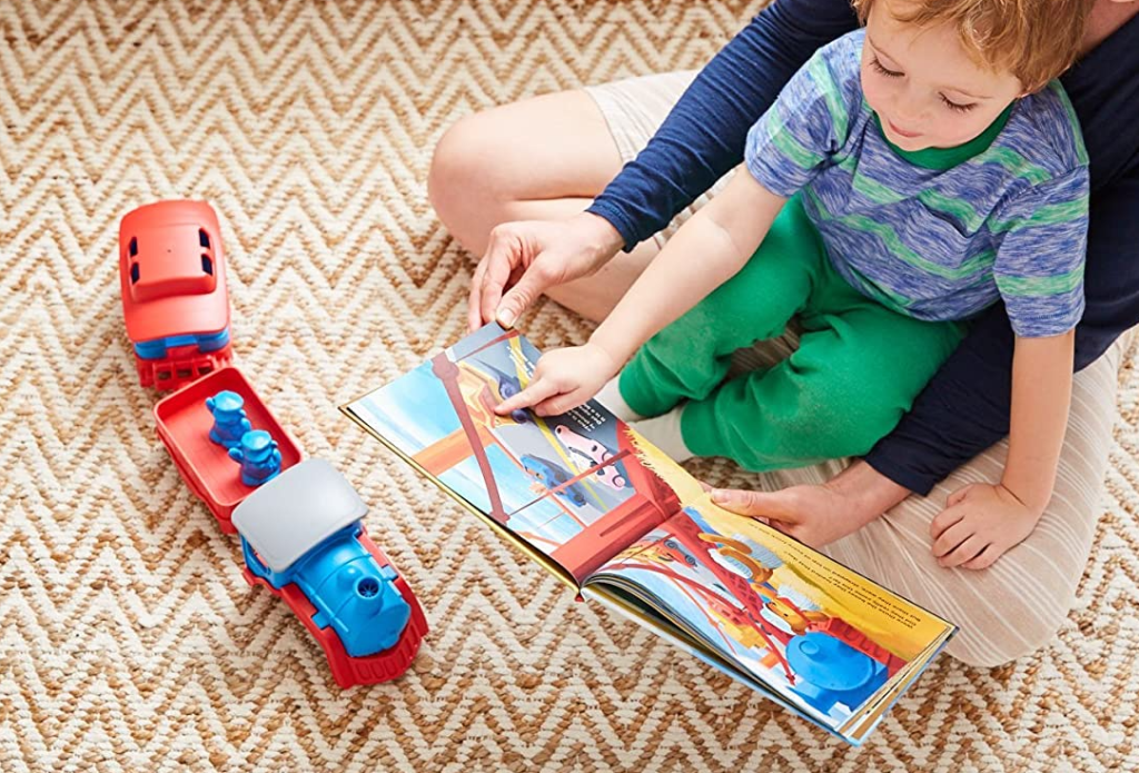 boy looking at a book next to a train