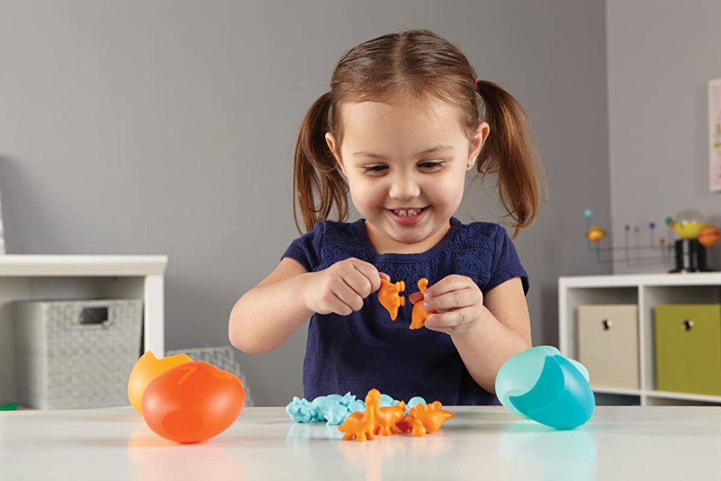 girl playing with toy dinosaurs