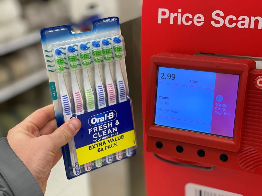 hand holding a package of Oral-B Fresh and Clean Toothbrushes