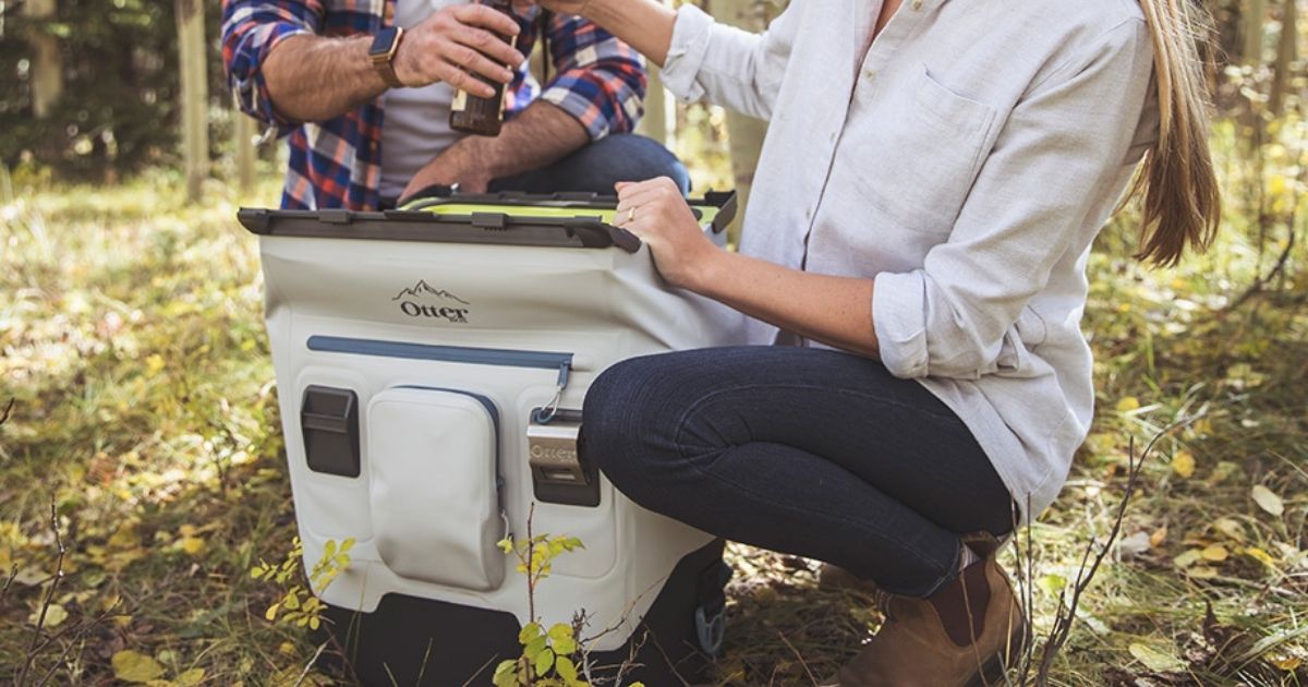 woman kneeling next to a otterbox cooler