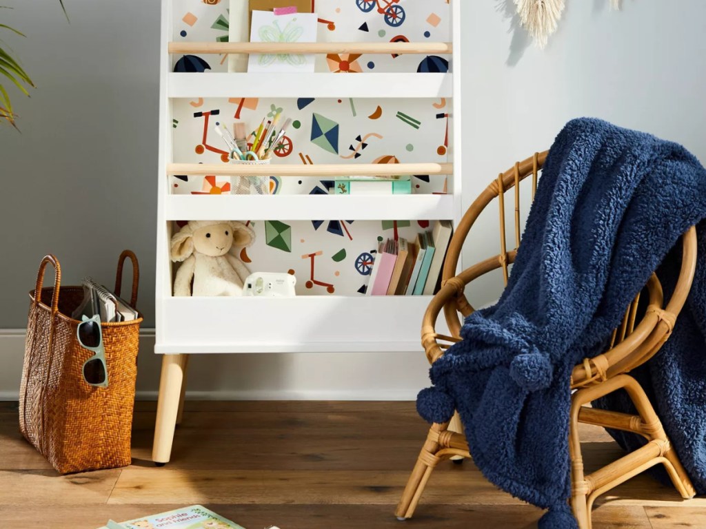 Pillowfort blue pompom blanket across a wicker chair in a child's room