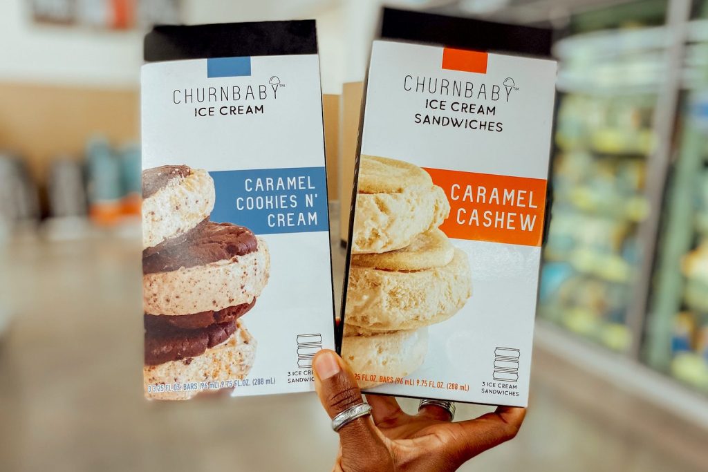 hand holding two boxes of ice cream sandwiches in store freezer aisle