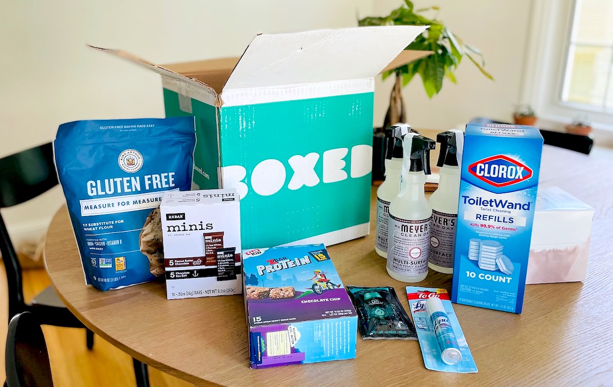 spread of household essentials and food on dining room table from boxed with promo code