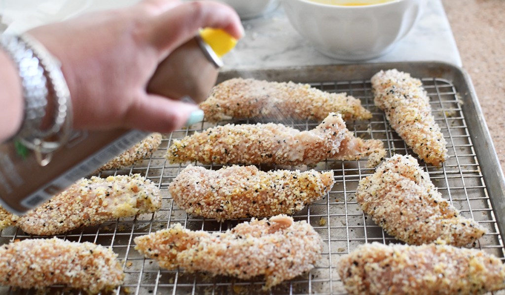 spraying everything bagel chicken tenders with coconut oil