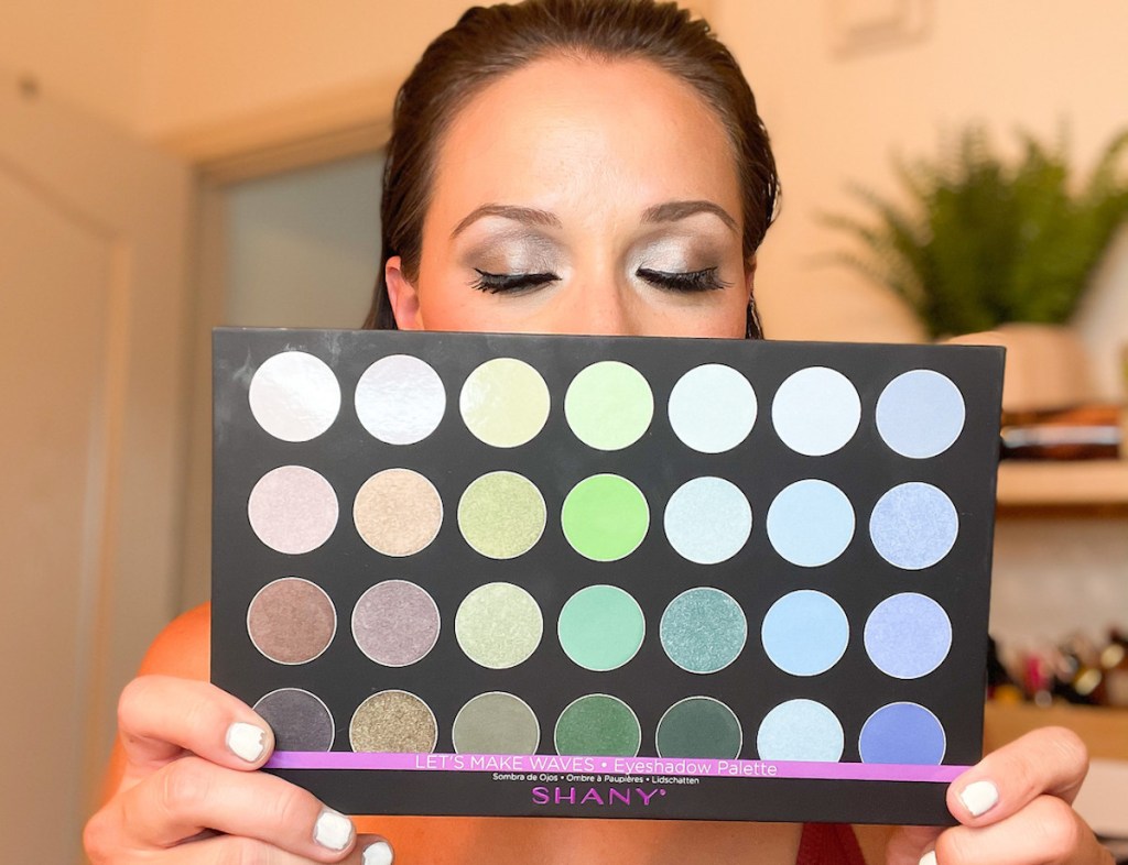 woman holding up shany cosmetics makeup palette with glam eyeshadow on face