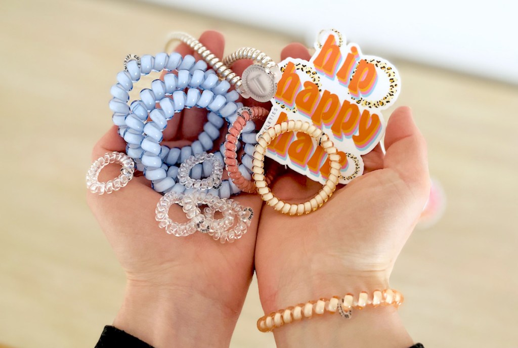 hands holding pile of colorful hair ties with teleties rainbow sticker