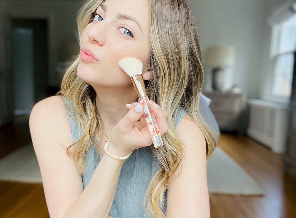 woman using floral makeup brush on cheek