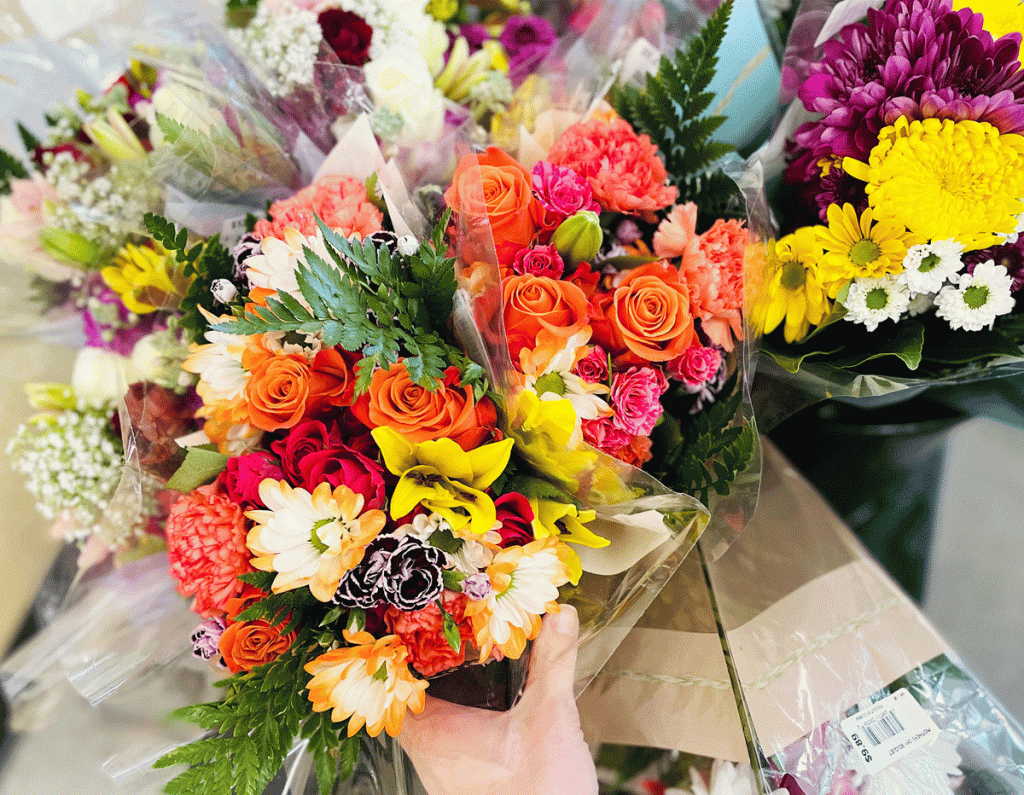 woman reaching fro bouquets of flowers at aldi