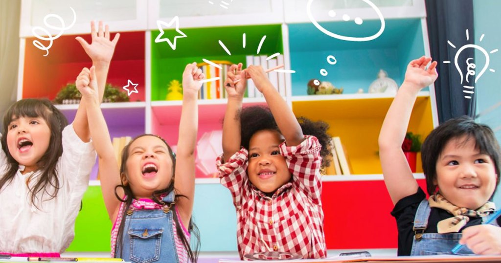 kids sitting at table with hands up in air