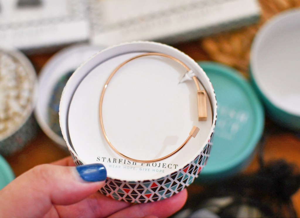 woman holding rose gold bracelet in a jewelry box